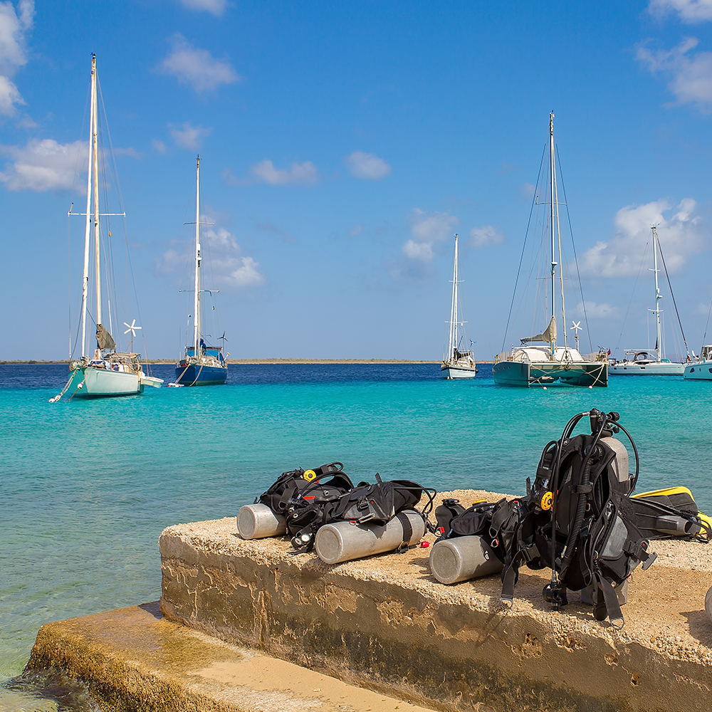Diving equipment on coast with boats on sea on the Divepricer listing site